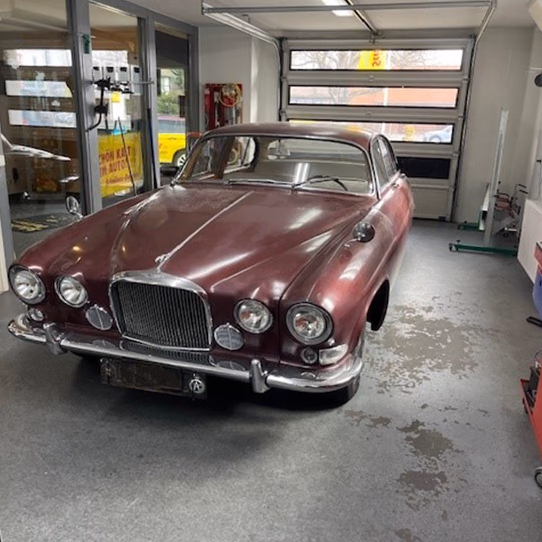 Dunkelroter Oldtimer-Jaguar ohne Windschutzscheibe in einer Werkstatt