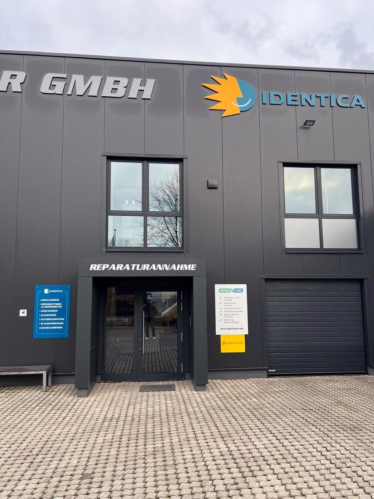 Gebäude mit Identica-Logo und Eingang „Reparaturannahme“ samt Scheiben-Doktor-Schild