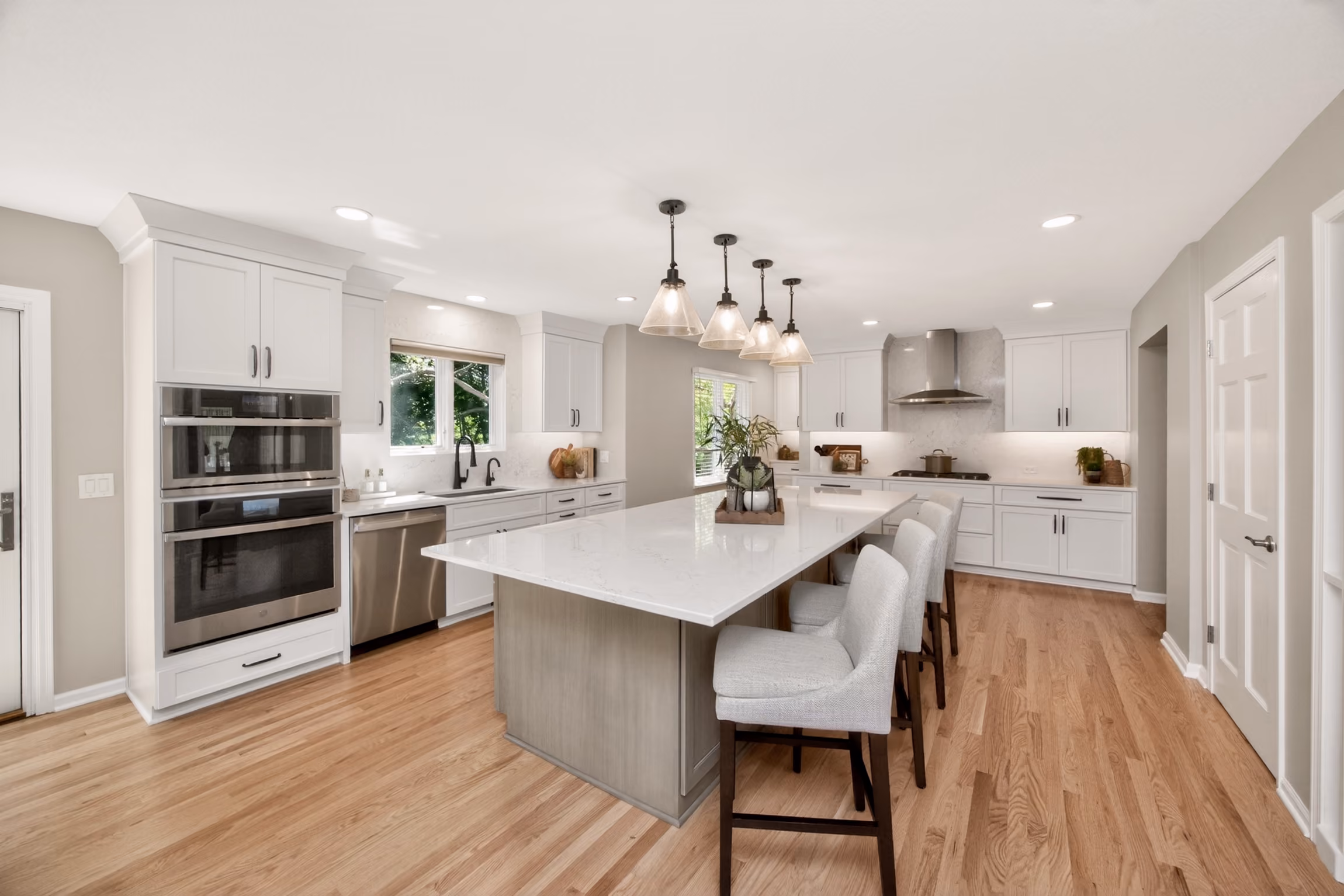 Gorgeous kitchen expansion and remodel with white cabinetry, white quartz countertops and a large gray island.