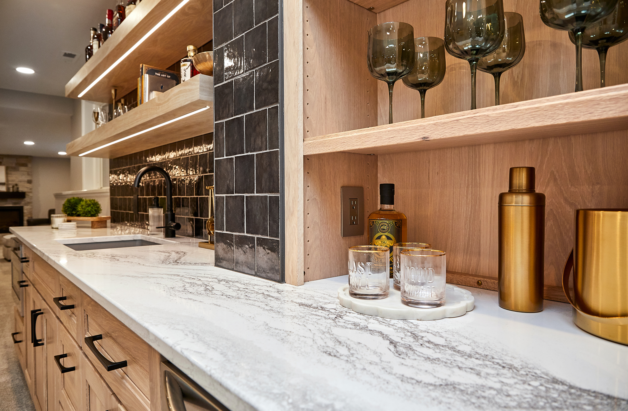 Basement wet bar with natural cabinets and black backsplash tile
