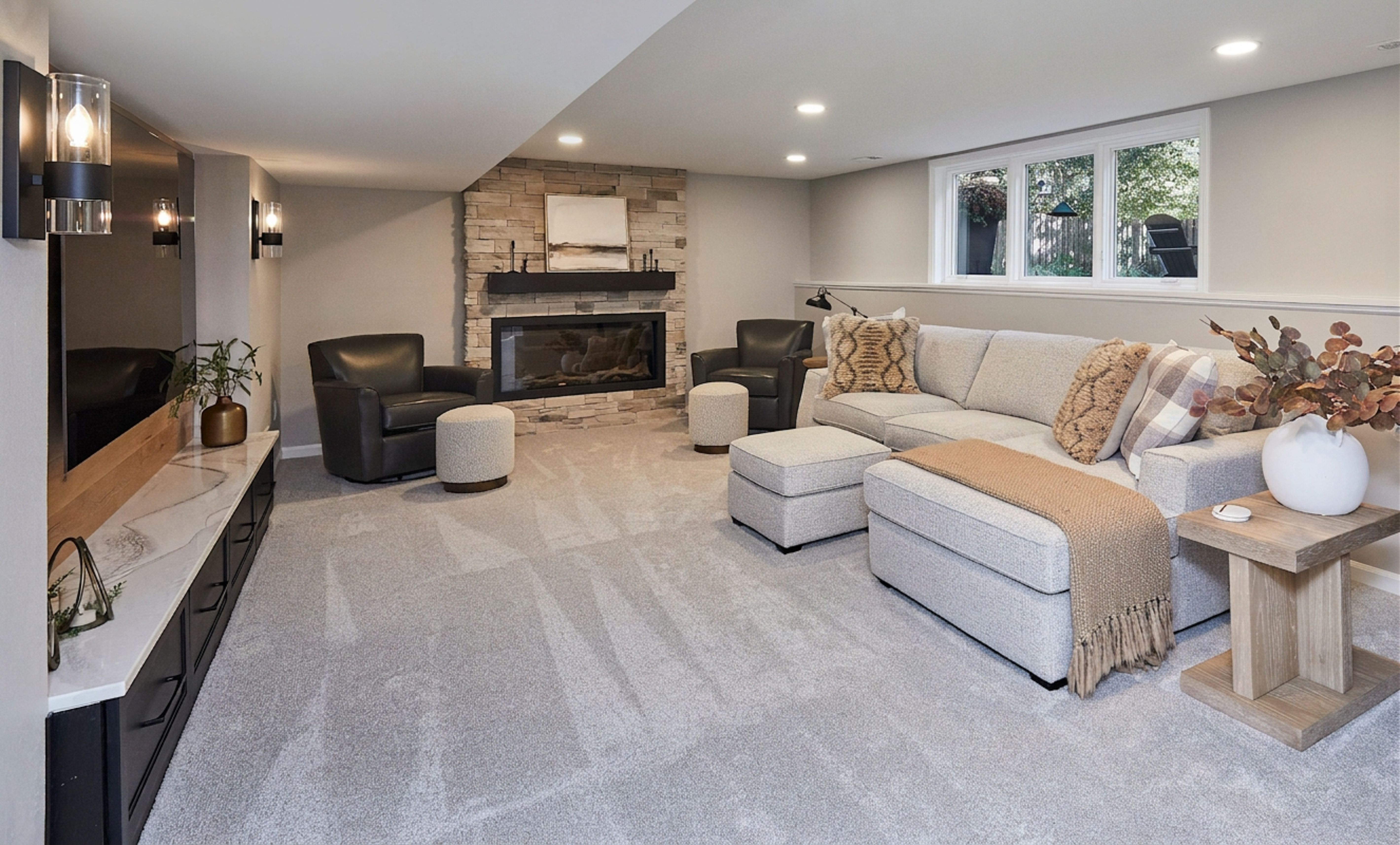 Basement remodeled family room with stone fireplace and TV feature wall