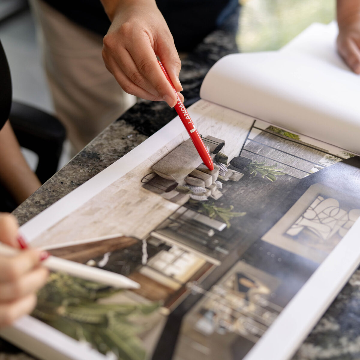 Asesor señalando con una pluma de Landmark los interiores del brochure de Costa Norte