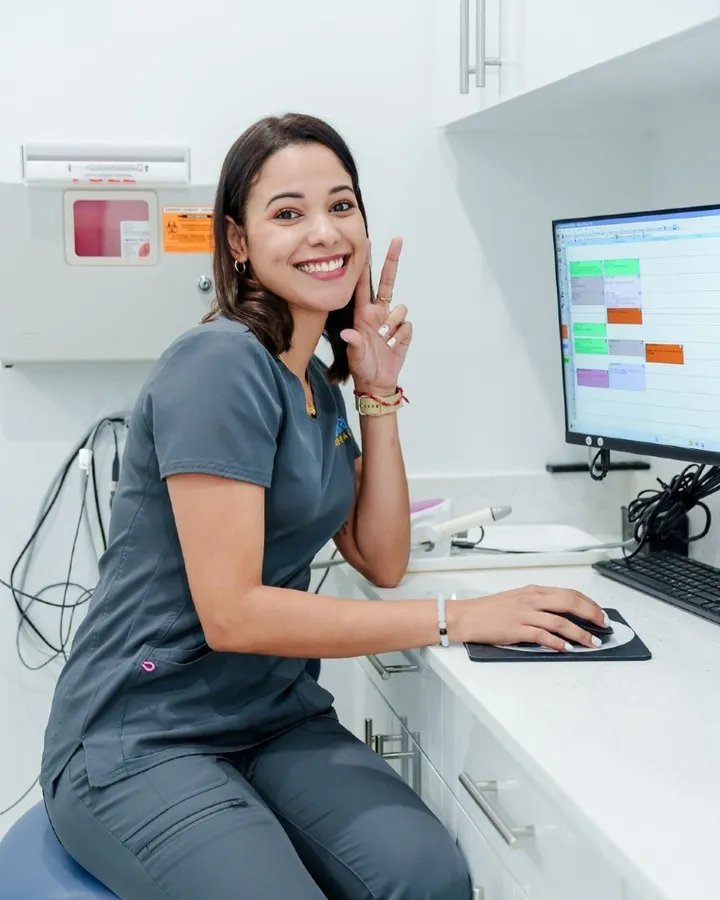 Dental hygienist at Jonari Dental in Cooper City smiling and holding a peace sign. Book an appointment for teeth cleaning and preventive dental care.