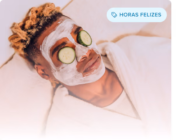 Homem sorridente com uma máscara facial preta deitado com os olhos fechados, desfrutando de um tratamento de spa.