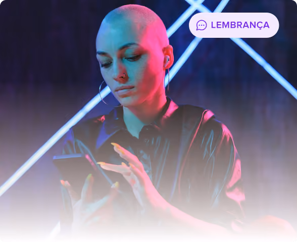 Pessoa com a cabeça raspada e brincos de argola usando fones de ouvido, olhando e usando um smartphone com luz de néon azul e rosa ao fundo.