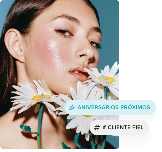 Close-up de uma mulher com pele brilhante segurando margaridas brancas contra um fundo azul-petróleo.