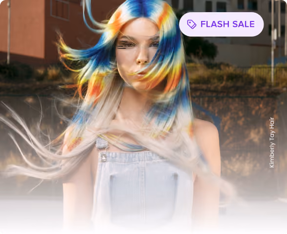 Woman with long hair dyed in vibrant blue, yellow, and orange hues blowing in the wind, wearing denim overalls.