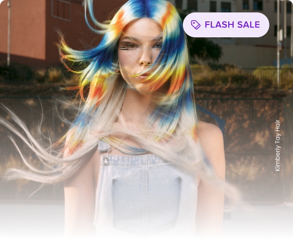 Woman with long hair dyed in vibrant blue, yellow, and orange hues blowing in the wind, wearing denim overalls.