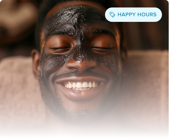 Smiling man with a black facial mask lying back with eyes closed and a relaxed expression.