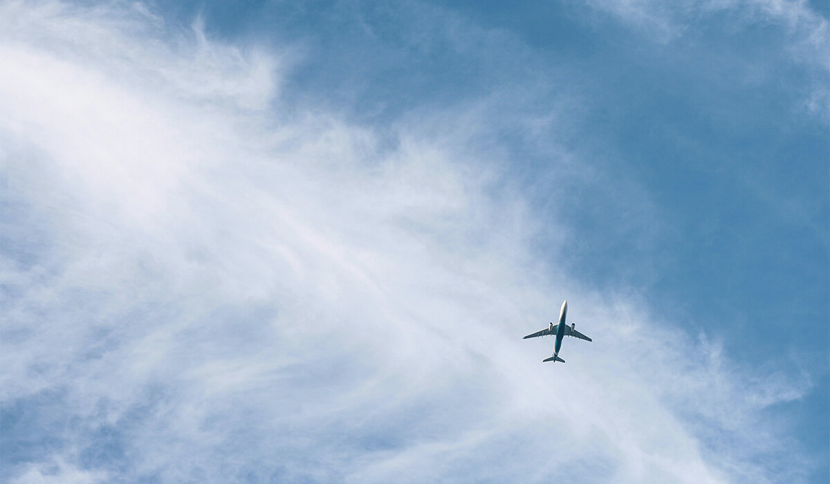 Plane flying in a blue cloudy sky.