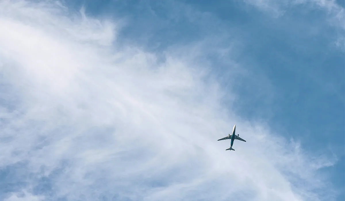 Plane flying in a blue cloudy sky.