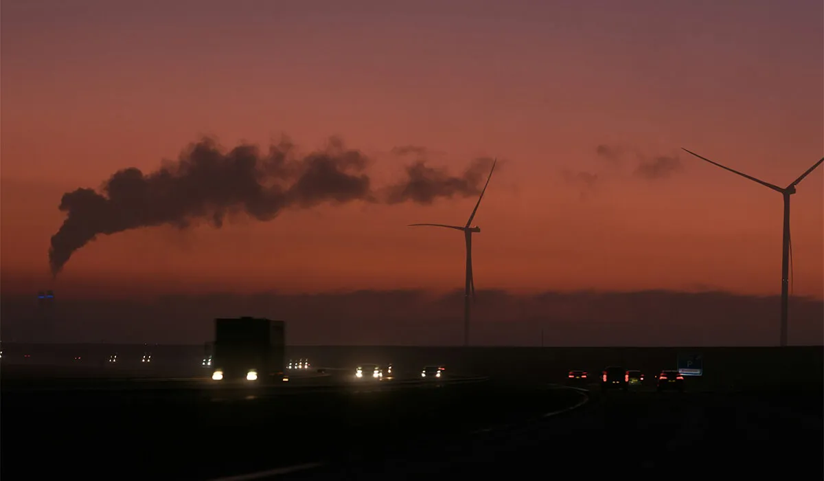 Smokestack and wind turbines at sunset. 