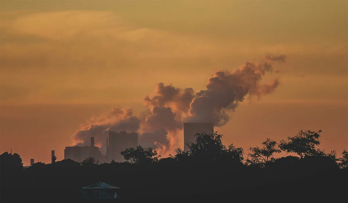 Power plant emitting smoke into the sky at sunset.