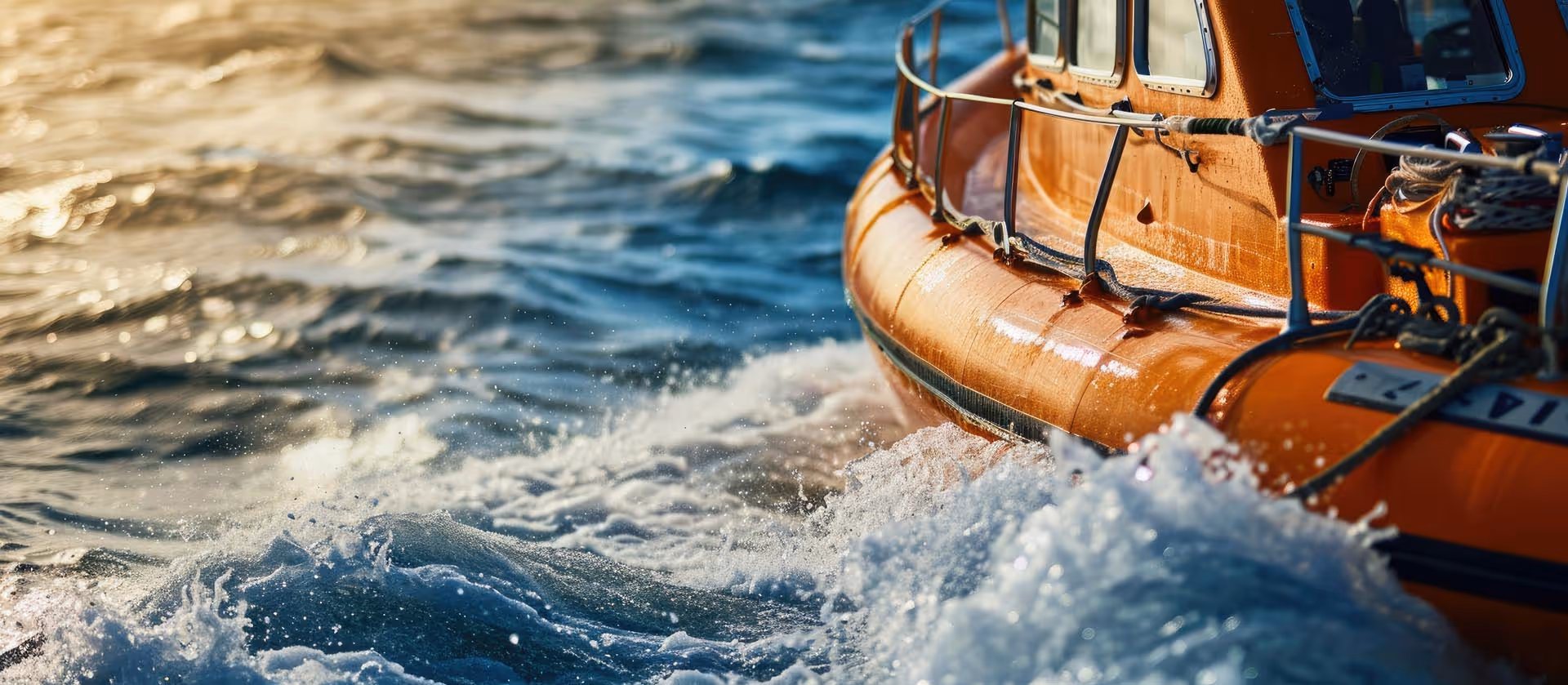 Close-up of an orange boat moving through choppy water with waves splashing against its side.