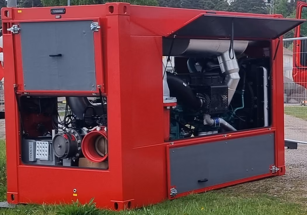 Large red industrial machine with open panels showing engine and mechanical components indoors.