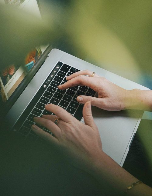 A woman hands typing on a laptop.