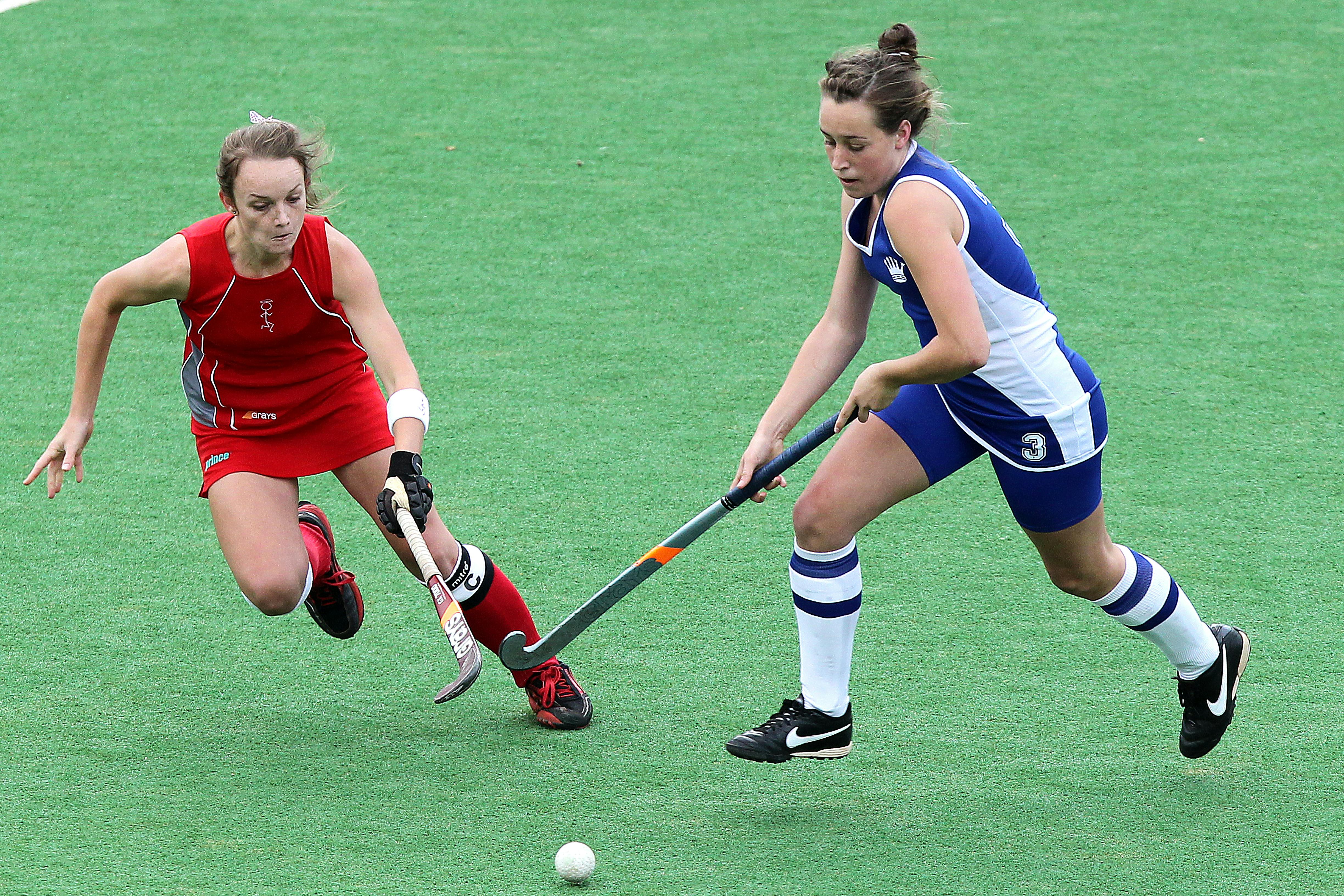 One field hockey player tackles another player
