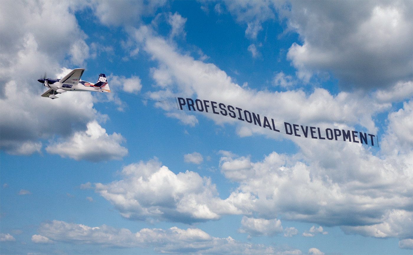 A small plane flying amid light cloud in a blue sky, towing a banner which reads "Professional development"
