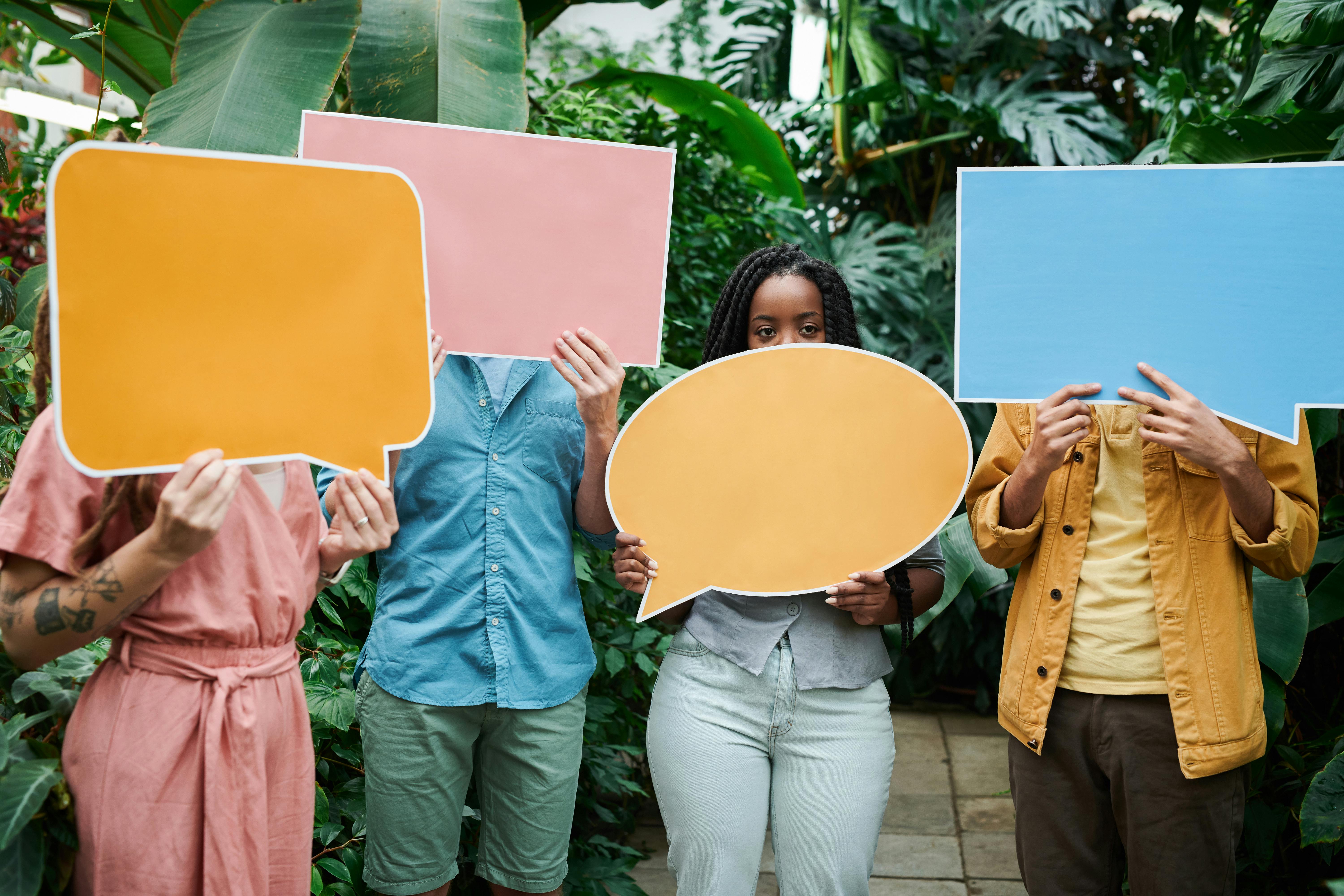 Four different people hold up colourful blank speech bubbles representing opinions. Photo by fauxels: https://www.pexels.com/photo/photo-of-people-holding-sign-board-3228837/