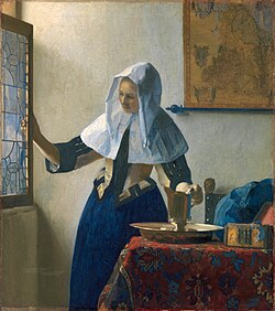 Johannes Vermeer c.1662 "Young woman with a water jug". Standing at an open window, a young woman begins her day. A gilt silver pitcher and basin stands on the table, ready for her to wash. Linen coverings protect her hair and blue dress.