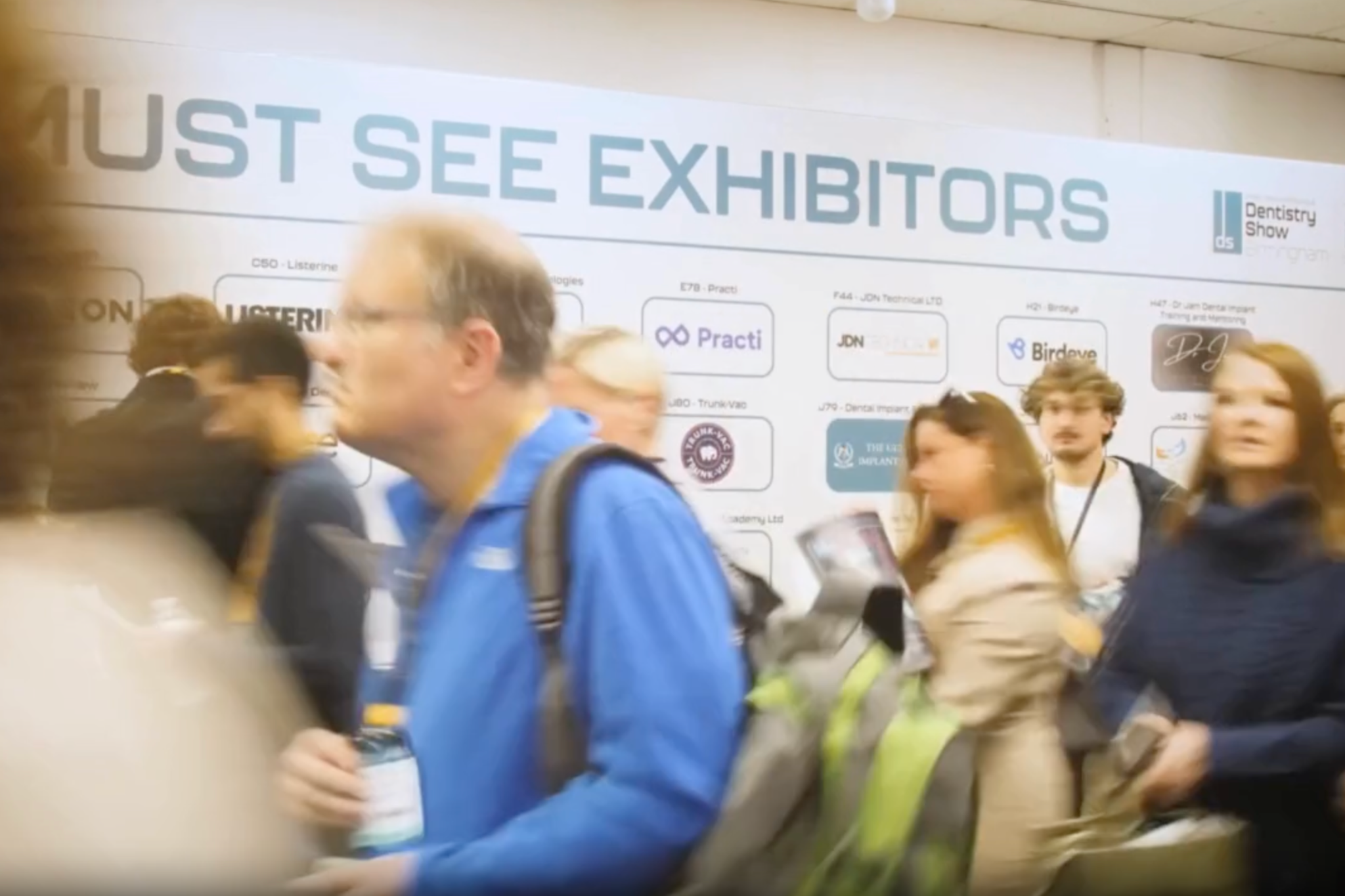 Dental professionals networking at exhibition stands British Dental Conference Birmingham discussing dental marketing and SEO