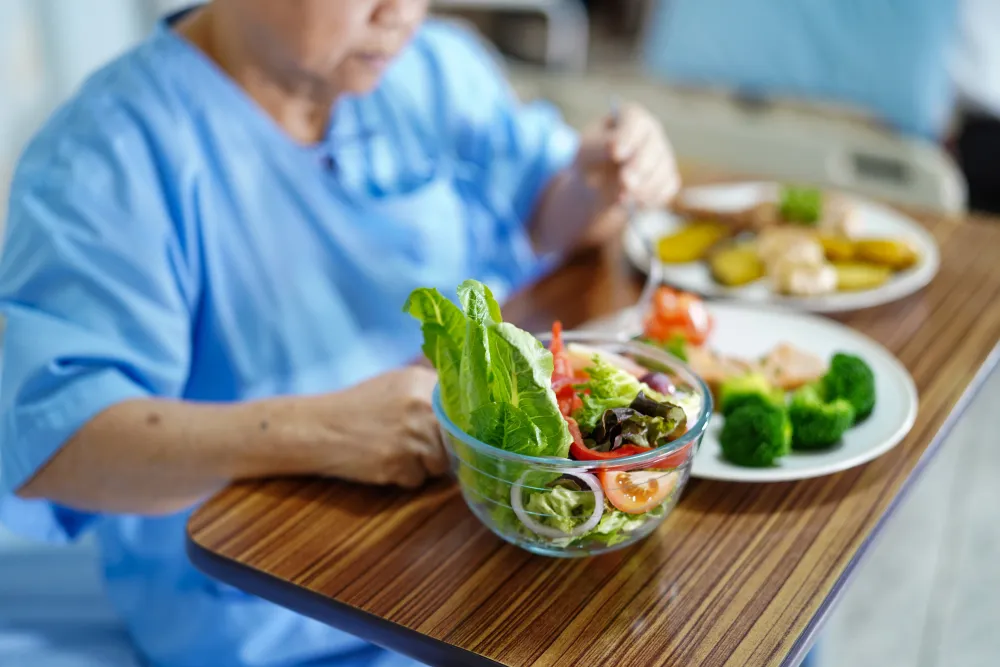 Präventive Ernährung - Eine ältere Dame bereitet sich ausgewogene Mahlzeiten zu.