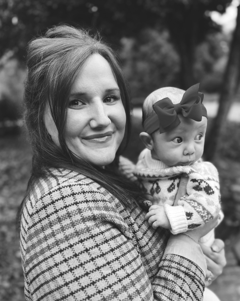 A black and white picture of Ellen McDowell smiling, holding a baby.