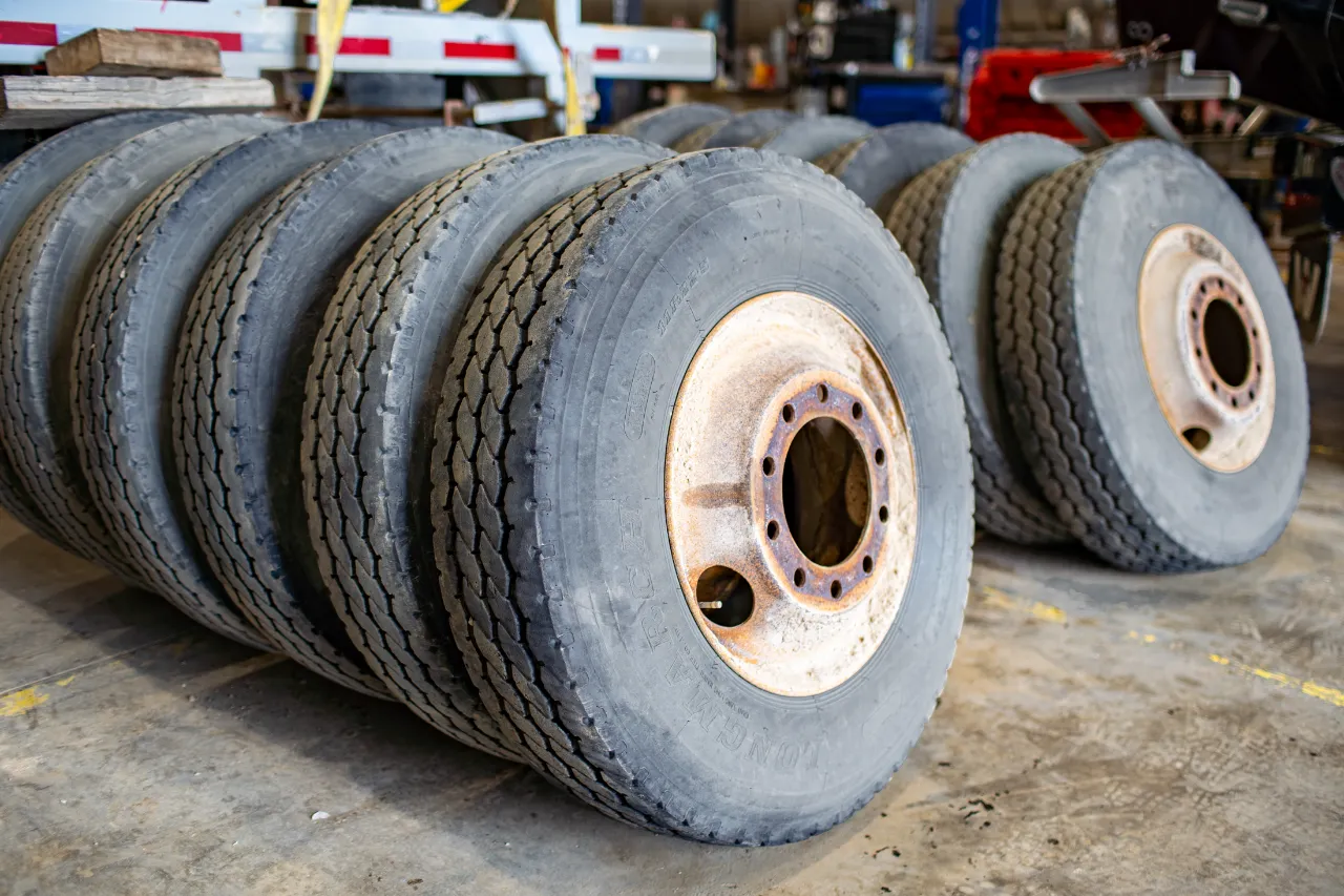 LONG MARCH heavy-duty tire set with worn treads and rusty rims in a truck repair bay.