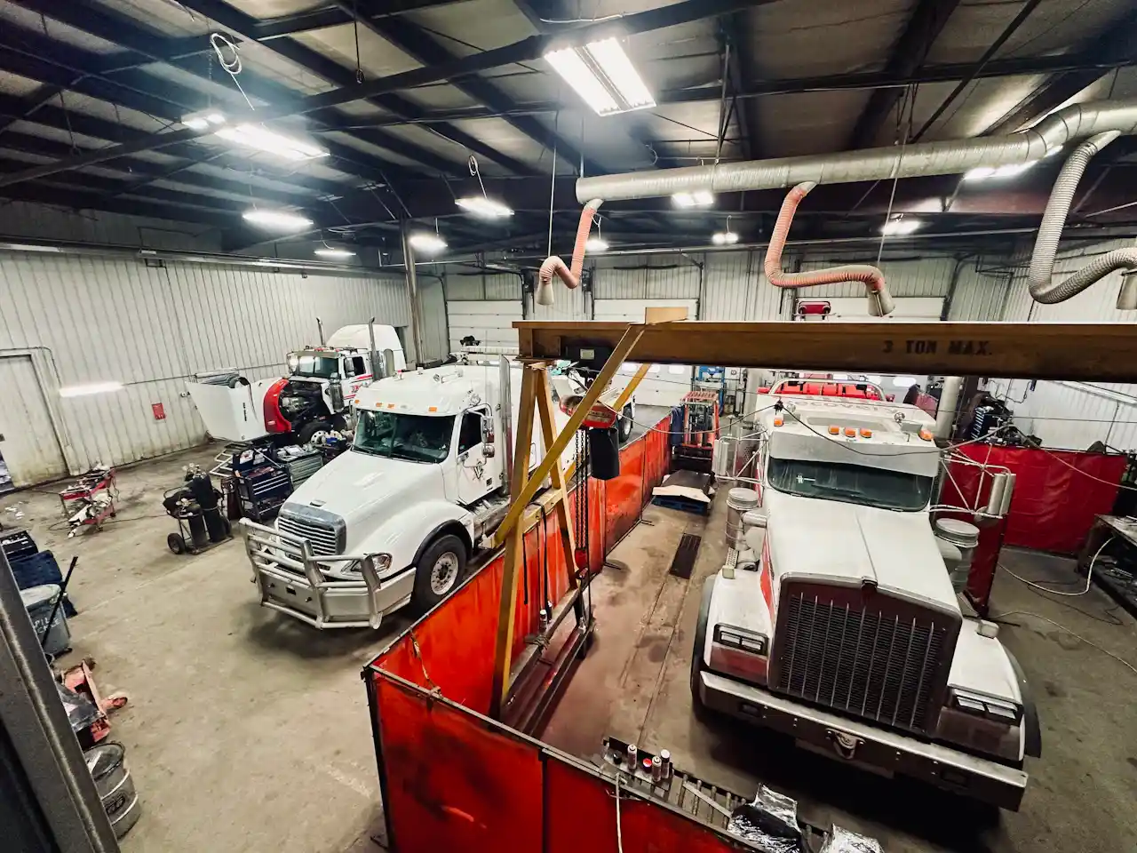 CVIP inspection facility with multiple heavy-duty trucks in service bays undergoing commercial vehicle safety and compliance inspections.