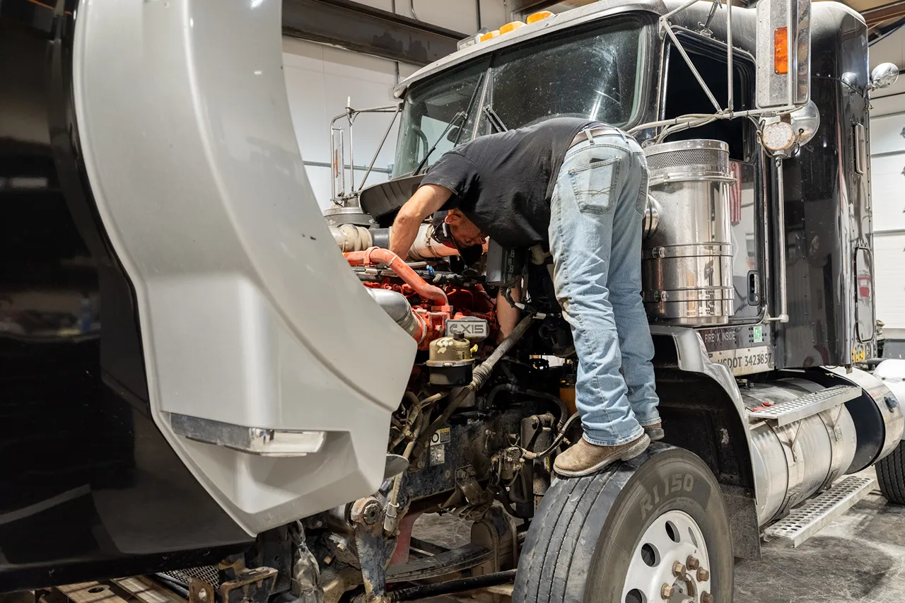 Heavy-duty repair technician works on a semi-truck engine during an engine conversion for Northern BC and Alberta truck owners.