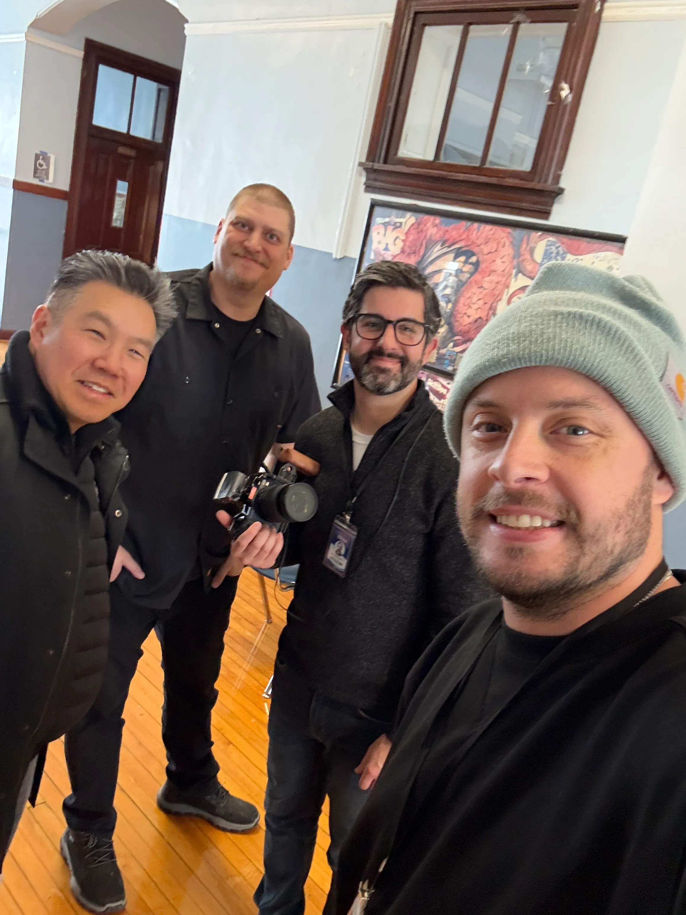 Four members of the production team gathered together inside a school, one holding a camera