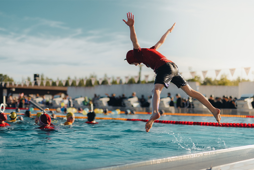 Poika hyppää uima-altaaseen