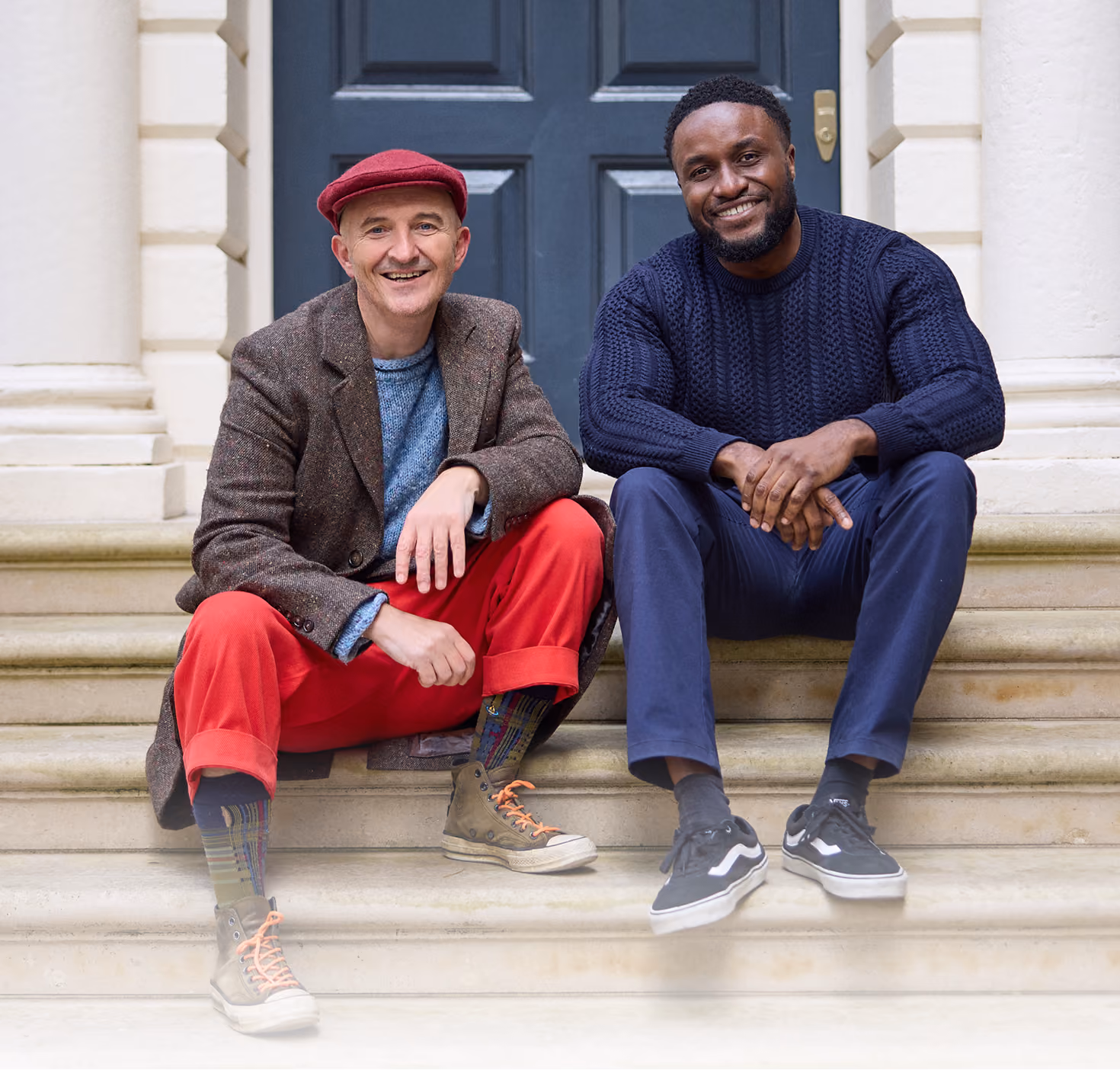 A photo of Feargus and Nnamdi side by side, sitting on some steps outside 