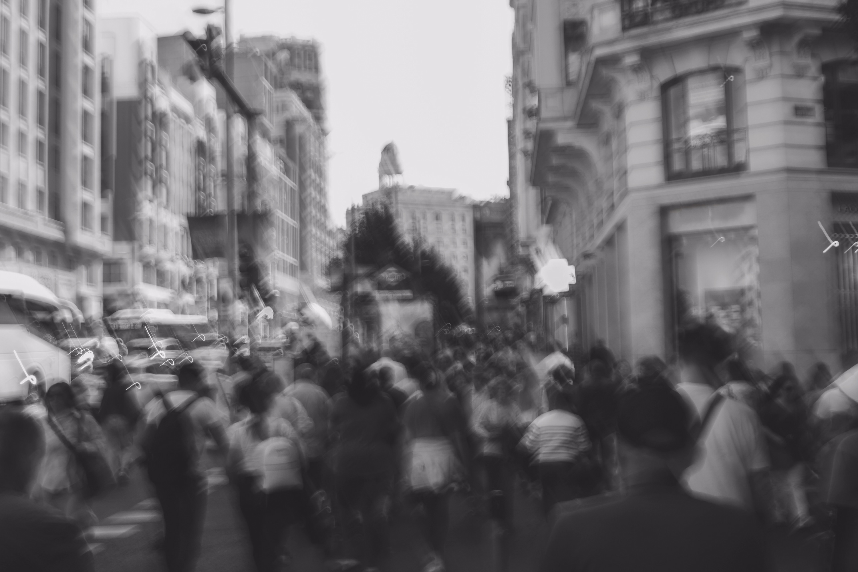 Black and white photo of people walking in a city street with motion blur.