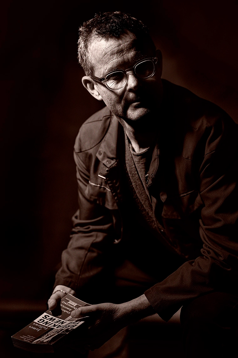 Kresten Schultz Jørgensen seated with a magazine in a dark portrait setting.