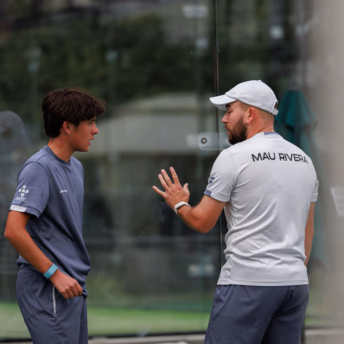 Two women wearing caps smiling and holding drinks, with a man partially visible in the foreground.