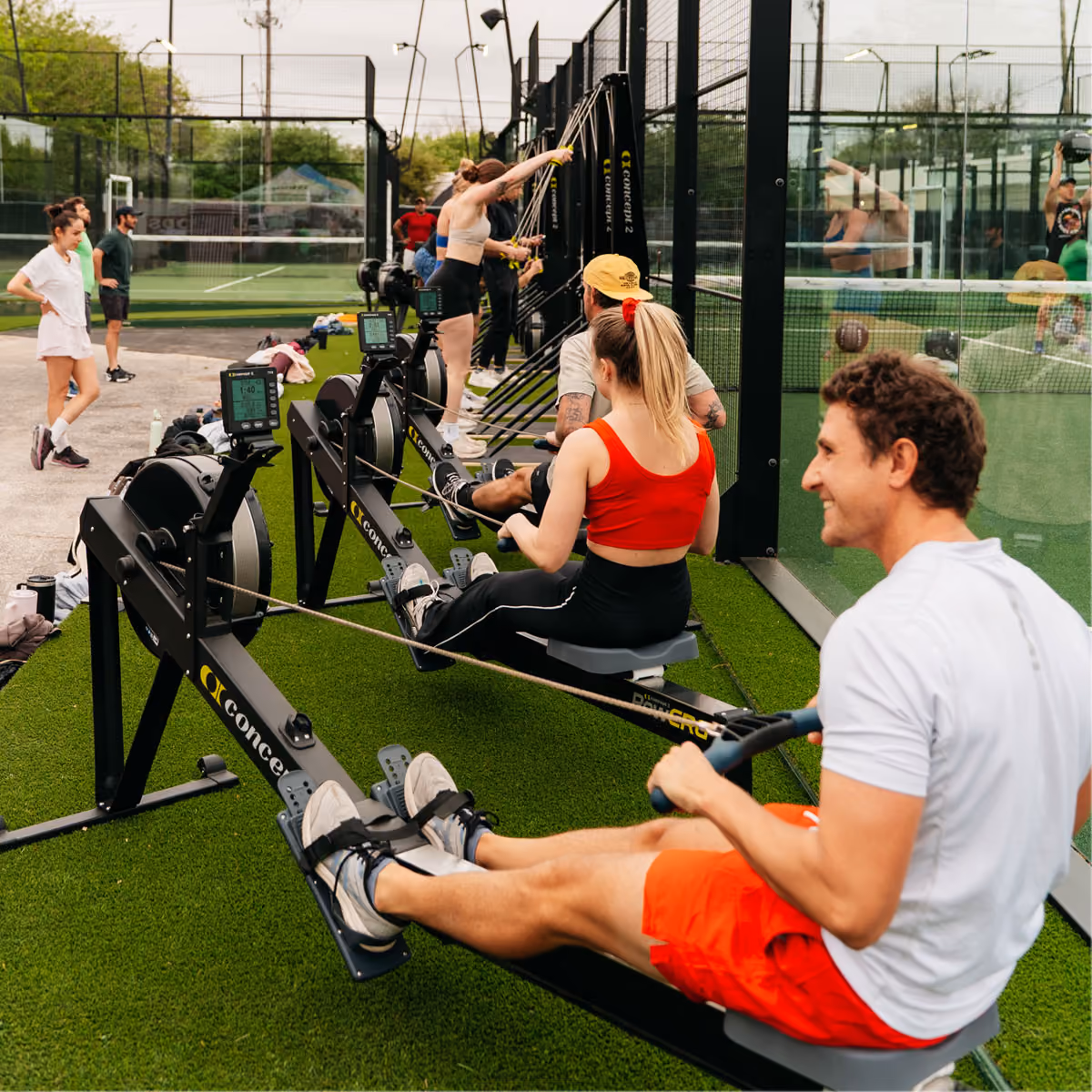 Tray of seven glasses filled with iced yellow-orange cocktails and black straws.