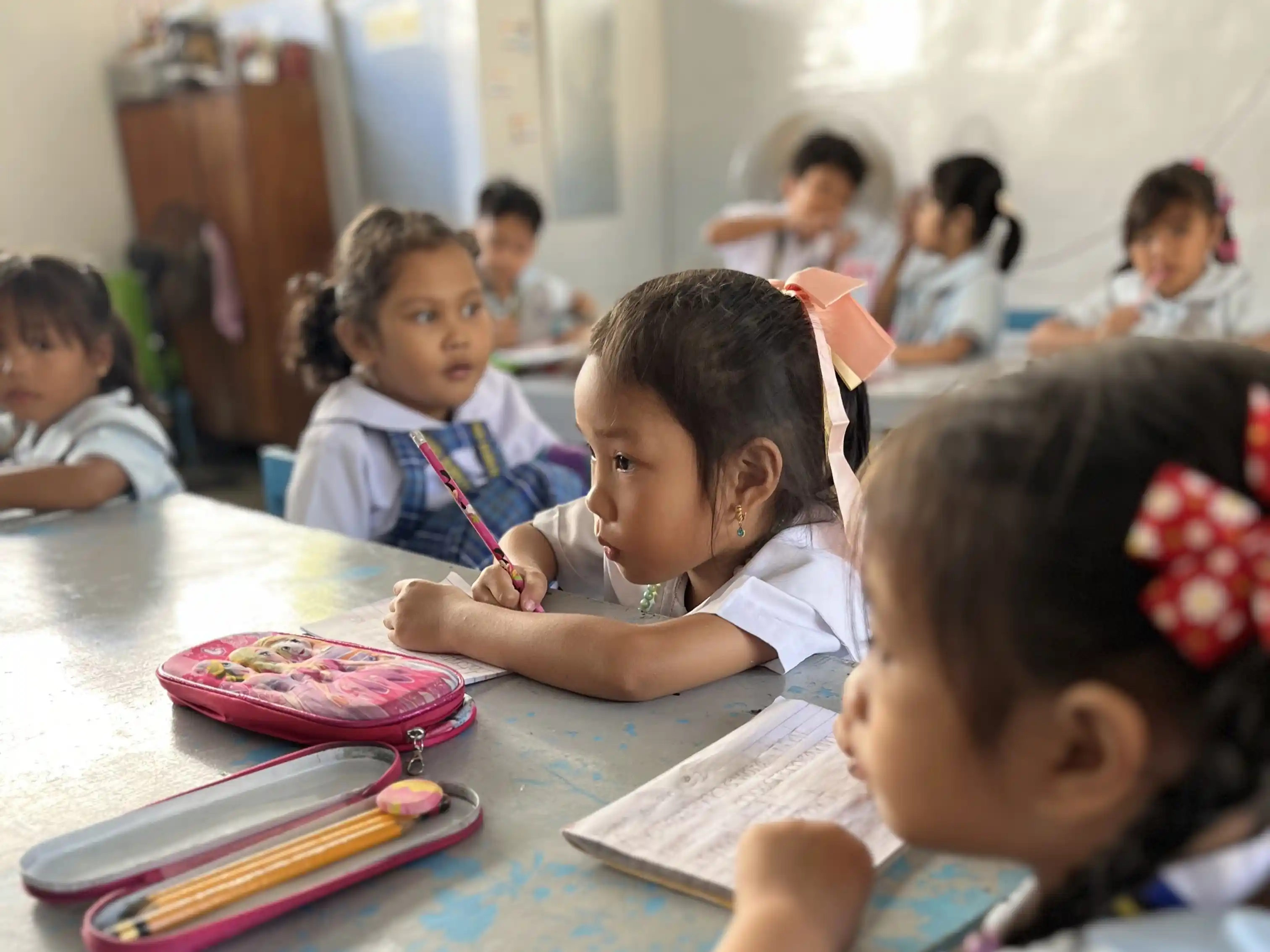 A cute kindergarten student listening to her teacher.