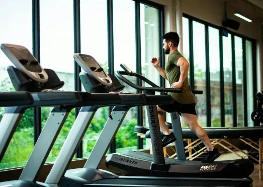 A man training on a treadmill in a bright gym
