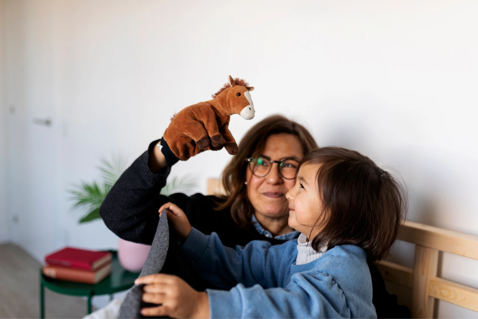 A woman and a child playing with a horse puppet