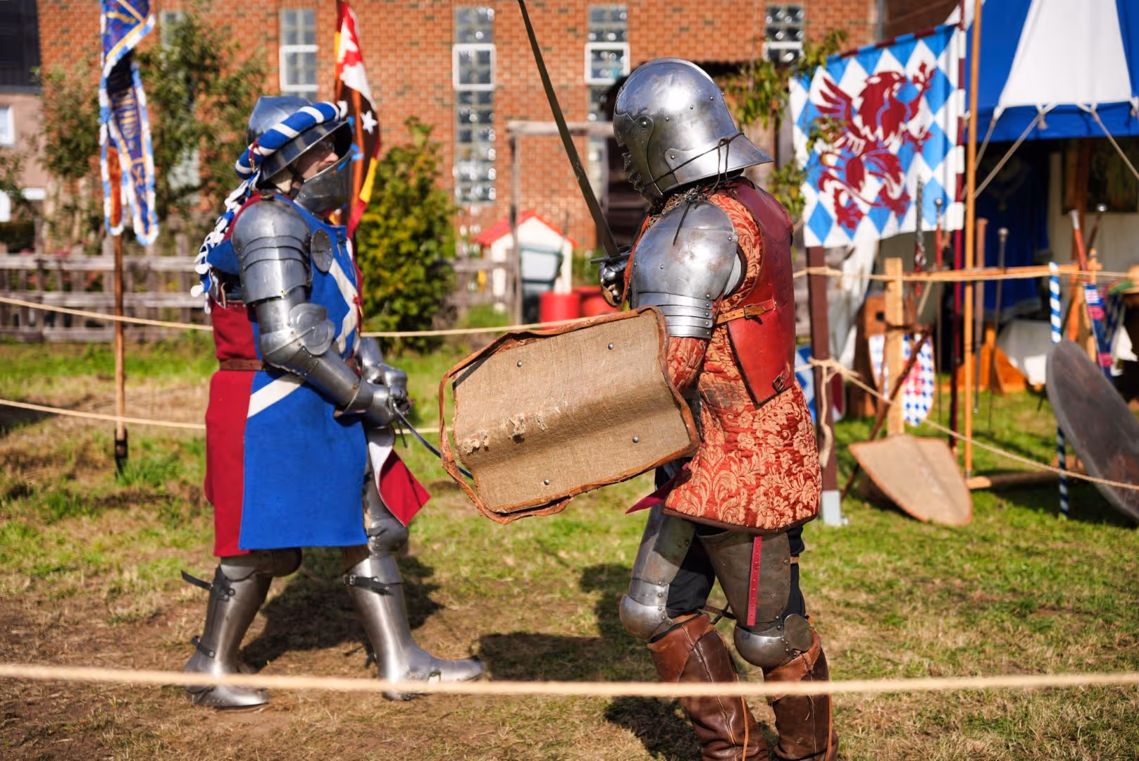 Deux combattants en armure médiévale s'affrontent lors d'une reconstitution en plein air.