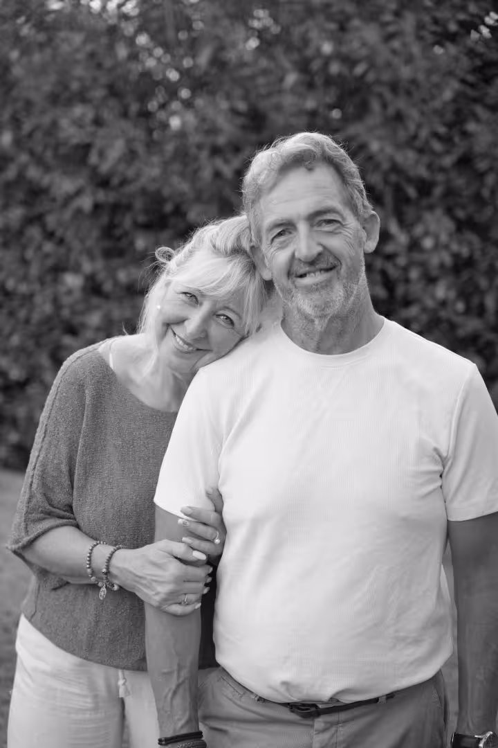 Couple souriant d'âge mûr, la femme appuie sa tête sur l'épaule de l'homme dans un jardin.