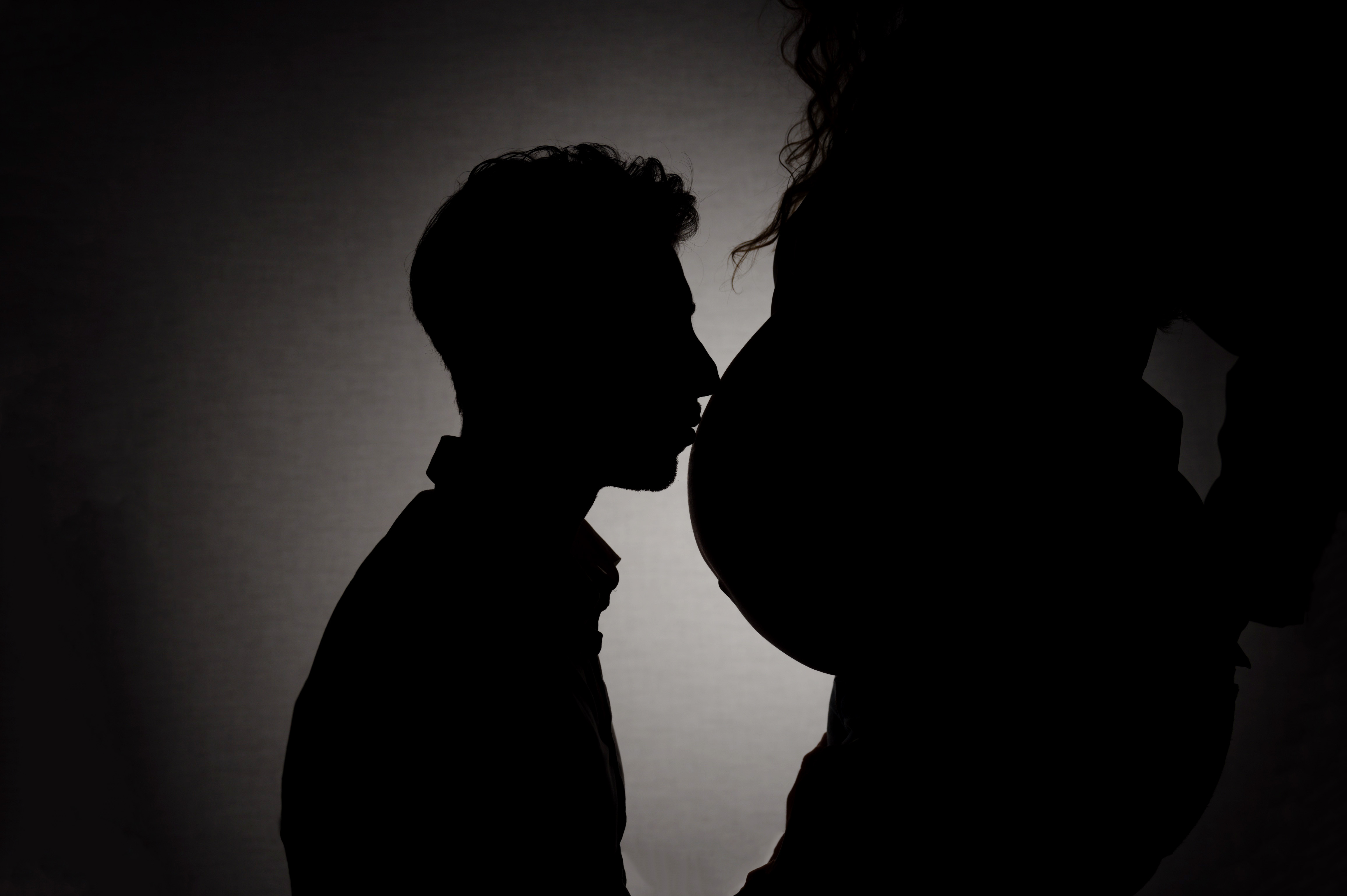 Silhouette d'un homme embrassant le ventre d'une femme enceinte.