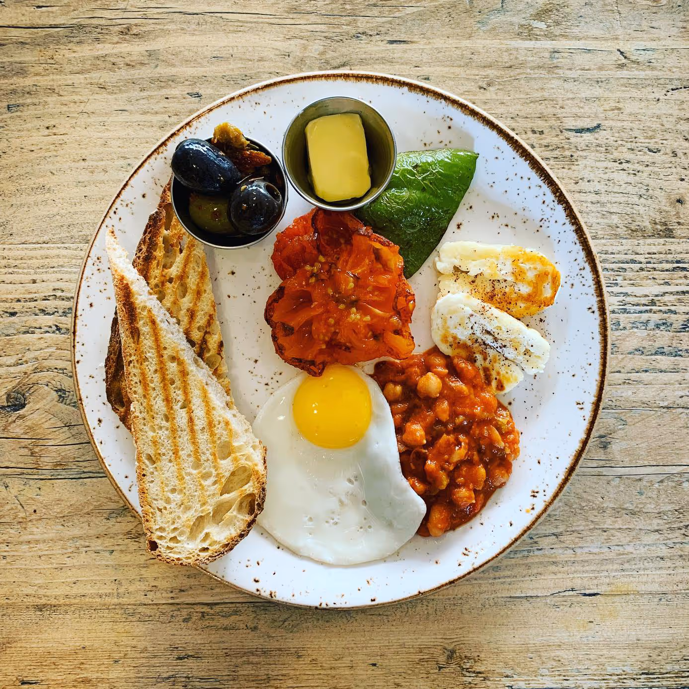Grilled halloumi and fried egg with roasted pepper, Isle of Wight tomato, Queen olives, house smoky beans with sourdough bread