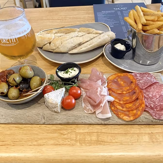 Charcuterie board with olives and a cold beer