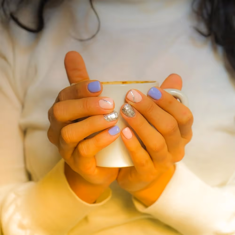 A woman in a white jumper cradling a hot mug of tea