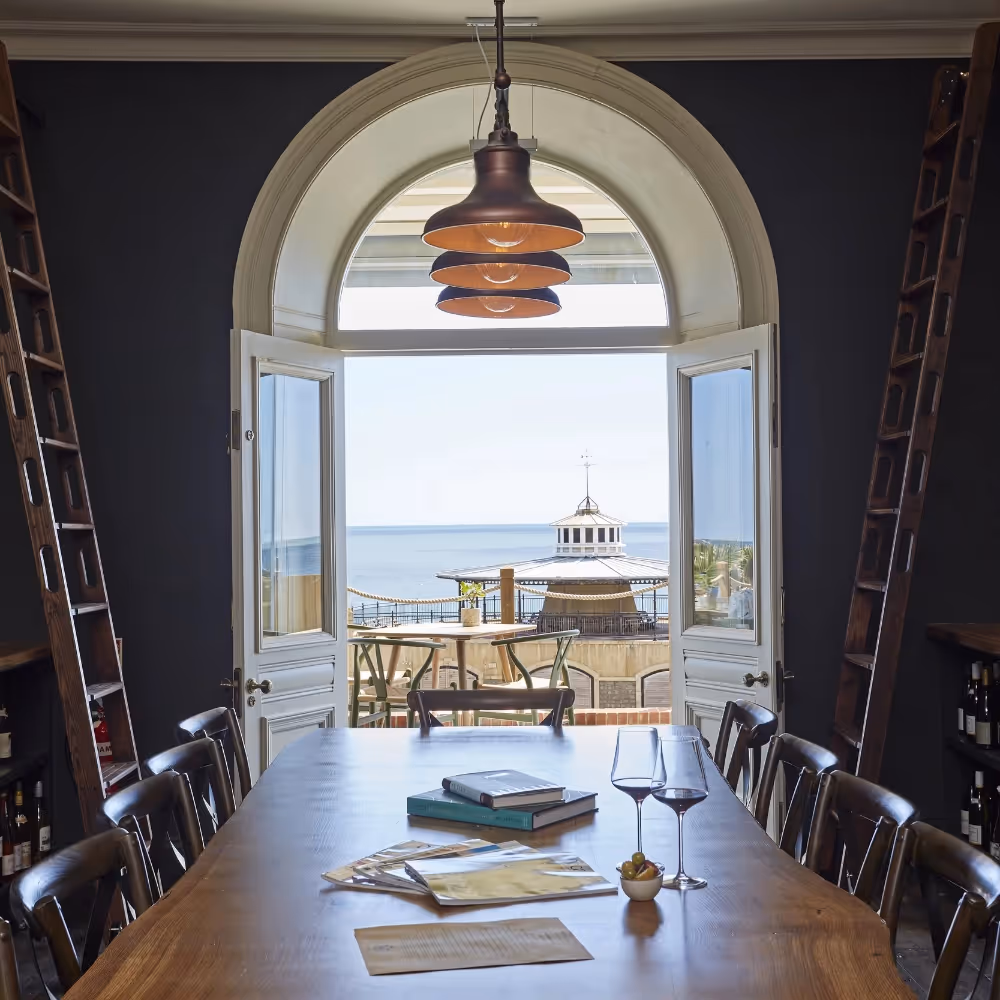 A long dining table with a glazed door overlooking the sea