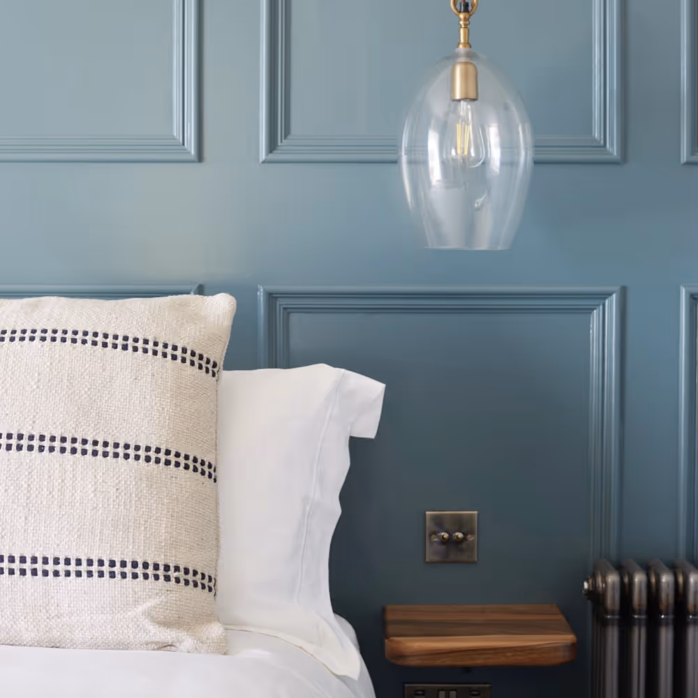 A bed with a blue panelled wall