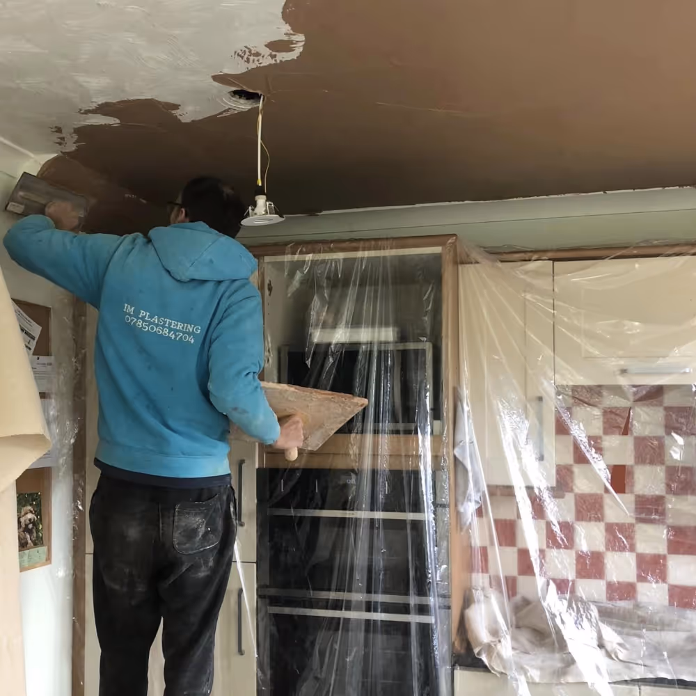 Man plastering a ceiling in a kitchen