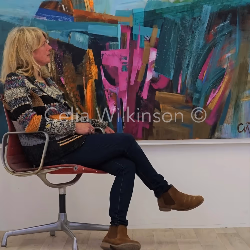 An artist sat in front of one of her abstract landscape painting